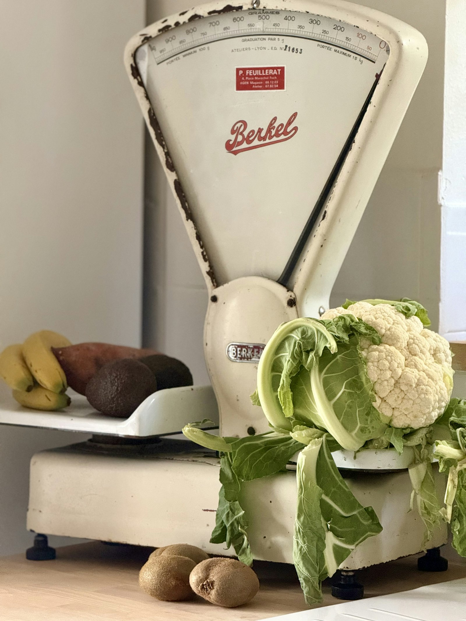 Old kitchen scale next to cauliflower and other fresh vegetables