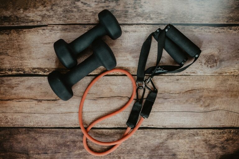 Dumbbells and a resistance band on a wooden table