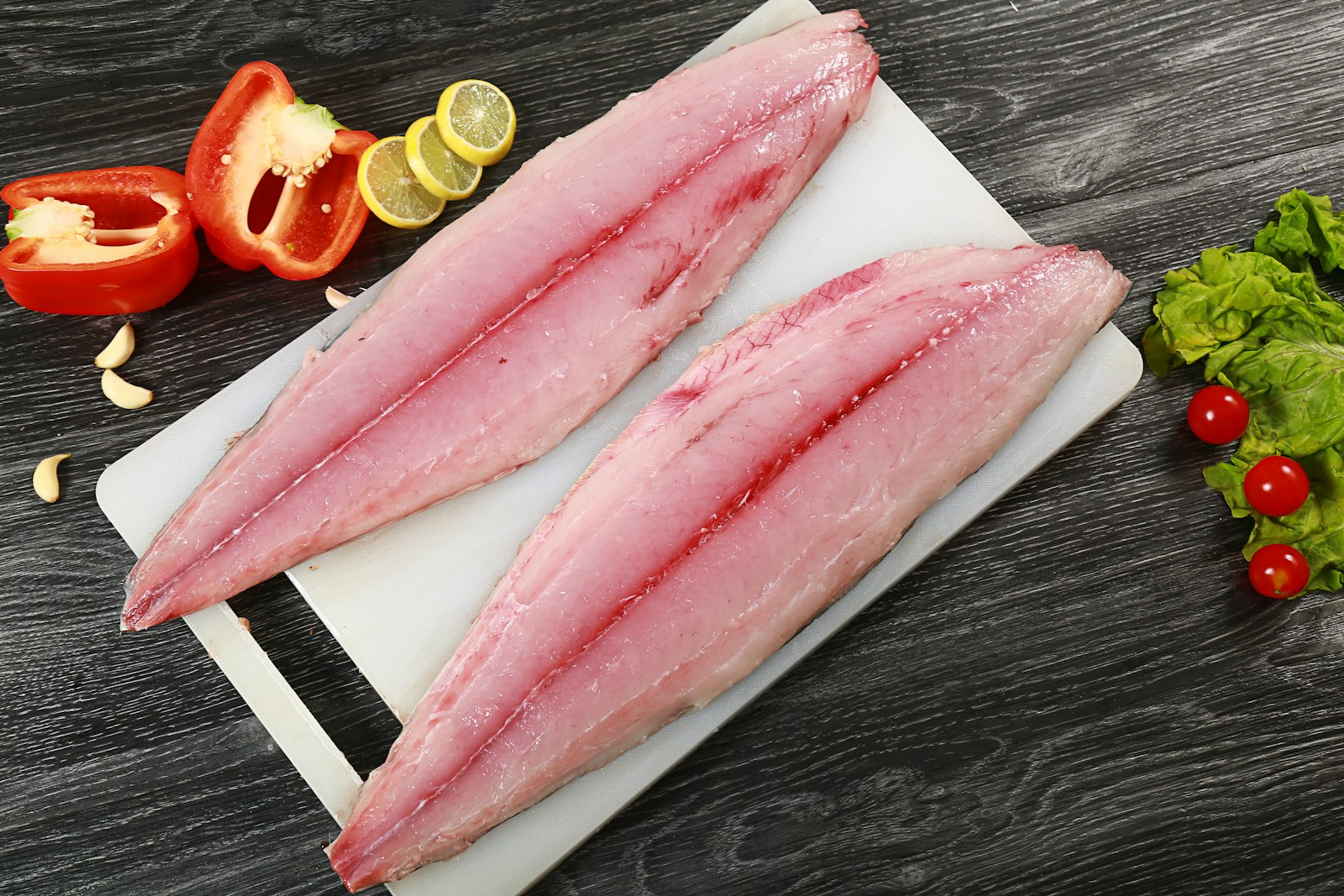 Dos filetes de pescado crudo sobre una tabla de cortar